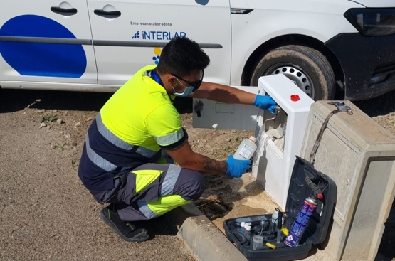 Un operario en cuclillas rellena una botella con agua de un grifo