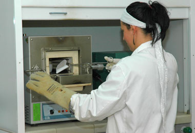 Una chica de espaldas introduce con unas pinzas un objeto en un horno